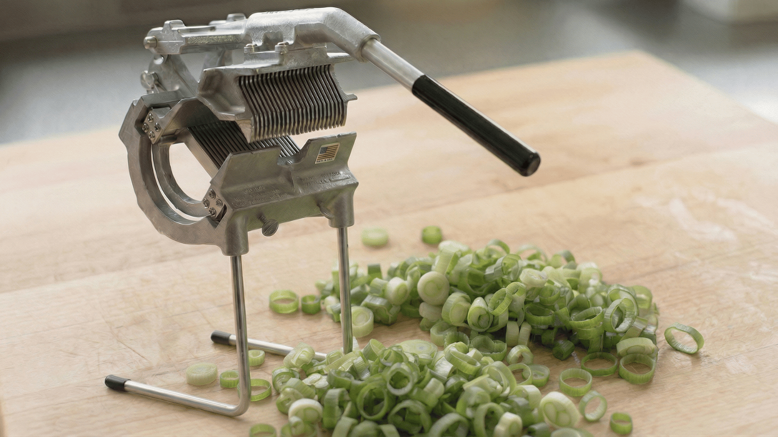 Nemco Green Onion Slicer Plus slicing fresh green onions into uniform 3/16-inch cuts on a commercial kitchen prep surface.