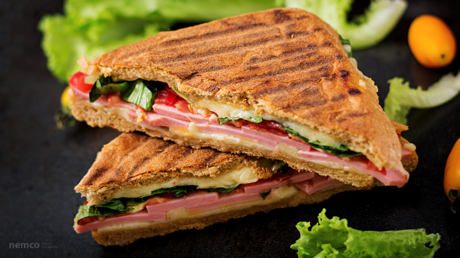 close up of a panini sandwich on a dark background with lettuce